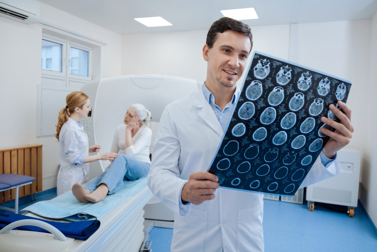 Positive results. Pleasant cheerful handsome doctor looking at the X ray image and being in a good mood while standing in the medical laboratory